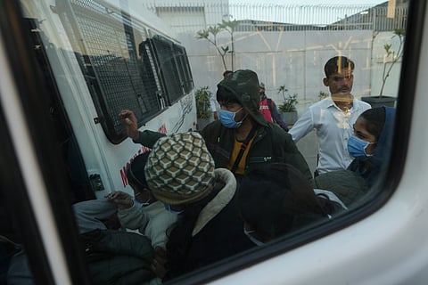 Immigrants, wearing masks, deported from the United States, who were among those who arrived in a US military plane Wednesday in Amritsar, enter a police vehicle at the Ahmedabad airport, India, Thursday, Feb. 6, 2025.
