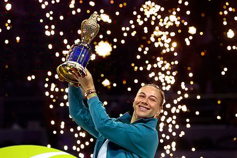 Amanda Anisimova of the US holds the winner's trophy on the podium after winning the 2025 WTA Qatar Open final tennis match at the Khalifa International Tennis Complex in Doha on February 15, 2025.