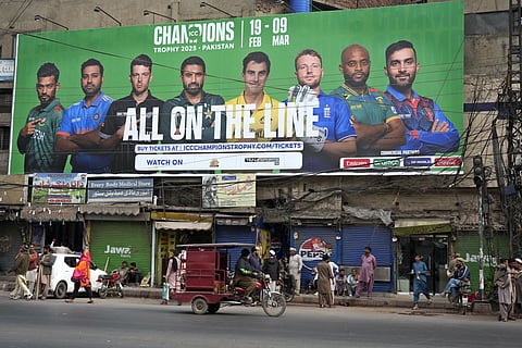 An auto-rickshaw drives past a billboard depicting portraits of the captains of participating cricket teams in ICC Champions Trophy 2025, installed at a roadside, in Lahore, Pakistan, Sunday, Feb 16, 2025.