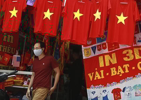 A man walks past a row of T-shirts printed with Vietnamese flags in Hanoi, Vietnam on July 30, 2020.