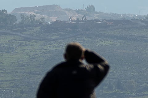 A Lebanese man watches bulldozers at work on the Hamamis hill, background, near the town of Khiam, southern Lebanon, Monday, Feb. 17, 2025.