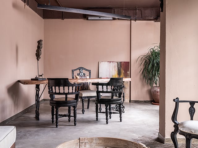 Live edge wooden table with ornate wrought iron legs and colonial chairs