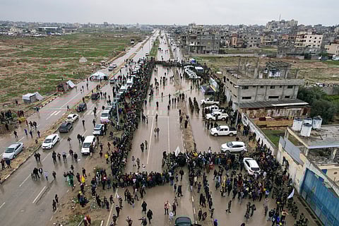 Palestinians gather as Hamas fighters deploy ahead of the planned release of Israeli hostages set to be handed over to the Red Cross in Nuseirat, central Gaza Strip, Saturday, Feb. 22, 2025.