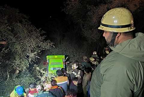 People gather near the site where a bus fell into a gorge at Manda area, in Jammu district, late Saturday, Feb. 22, 2025.