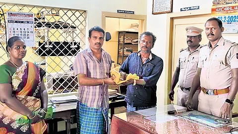 (From left) Jothi and Thangasamy hand over the money to Bala Murugan in the presence of Inspector Shyam Sundar on Thursday