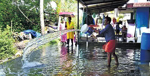A resident of Thanthoni Thuruth trying to clear the water that entered his house during the high tide.