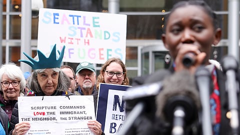 Retired reverend Carrol Jensen wears a hat mimicking the Statue of Liberty as Reverend Emilie Binja, a former refugee from the Democratic Republic of Congo, speaks during a rally outside the US District Court after a federal judge blocked President Donald Trump's effort to halt the nation's refugee admissions system on Tuesday, Feb. 25, 2025, in Seattle.