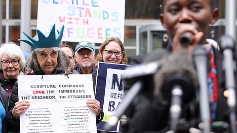 Retired reverend Carrol Jensen wears a hat mimicking the Statue of Liberty as Reverend Emilie Binja, a former refugee from the Democratic Republic of Congo, speaks during a rally outside the US District Court after a federal judge blocked President Donald Trump's effort to halt the nation's refugee admissions system on Tuesday, Feb. 25, 2025, in Seattle.