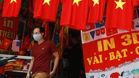 A man walks past a row of T-shirts printed with Vietnamese flags in Hanoi.