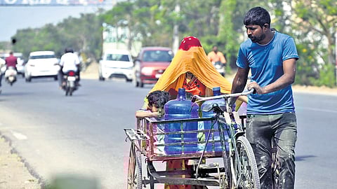 A man carries water cans on a tricycle along with his wife and child on a hot summer day in Karimnagar on Saturday