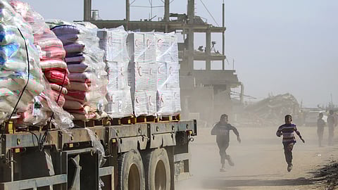 Palestinian children chase after a truck loaded with humanitarian aid as it drives through Rafah.