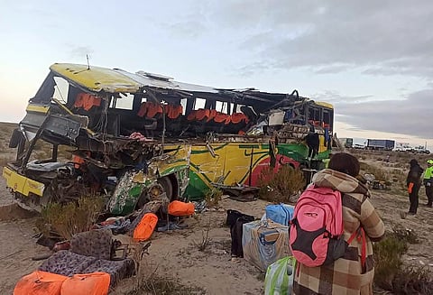 Handout picture released by Bolivian Police shows a woman walking close to the wreckage of a bus that collided with another one on a highway near Uyuni, Bolivia on March 1, 2025.