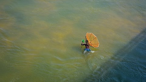 A man wades through waste-deep water to cast his net at Daya River on the outskirts of Bhubaneswar.