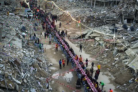 Palestinians sit at a large table surrounded by the rubble of destroyed homes and buildings as they gather for iftar, the fast-breaking meal, on the first day of Ramadan in Rafah, southern Gaza Strip, Saturday, March 1, 2025