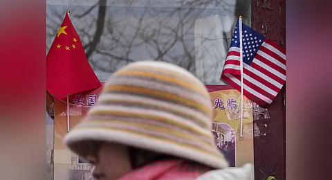 A woman walks by the Chinese and US national flags on display outside a souvenir shop in Beijing on Jan. 31, 2025.
