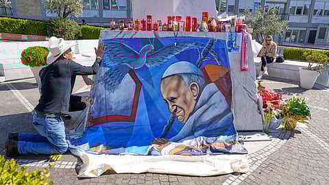 Mexican painter Roberto Marquez places a painting of Pope Francis he made outside the Agostino Gemelli hospital in Rome, Wednesday
