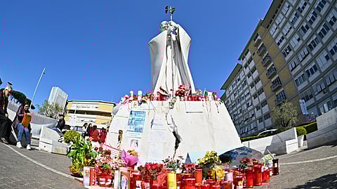 Candles are laid at the statue of John Paul II at the Gemelli University Hospital where Pope Francis is hospitalized with pneumonia, in Rome on March 6, 2025.