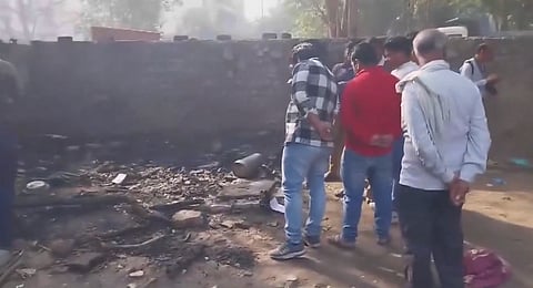 People observe the site where three laborers living in a tent were burned to death in a fire accident in Anand Vihar, Delhi, on Tuesday, March 11, 2025.
