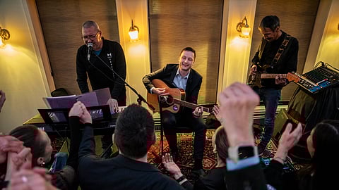 Chairman of Demokraatit, Jens-Frederik Nielsen, center, plays guitar as he reacts during the election party at Demokraatit by cafe Killut in Nuuk, early Wednesday, March 12, 2025.