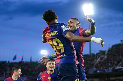 Barcelona's Raphinha (R) celebrates scoring his team's first goal with teammate Lamine Yamal during the UEFA Champions League Round of 16 second leg football match between FC Barcelona and SL Benfica on March 11, 2025.