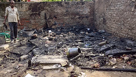 A man near the charred remains at the site after a fire gutted a makeshift tent near the AGCR Enclave at Anand Vihar, in New Delhi.