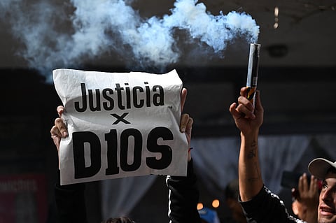 A fan holds a banner that reads in spanish 'Justice for D10s' as he waits outside the San Isidro court during the trial for the death of late Argentine football legend Diego Maradona in San Isidro, Buenos Aires province, Argentina on March 11, 2025.