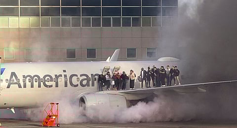 This image courtesy of Branden Williams shows passengers standing on the wing of an American Airlines plane as they are evacuated after it caught fire while at a gate at Denver International Airport in Denver, Colorado, March 13, 2025.