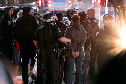 As light rain falls, New York City police officers take people into custody near the Columbia University campus in New York, Tuesday, April 30, 2024, after a building taken over by pro-Palestinian protesters earlier in the day was cleared, along with a tent encampment.