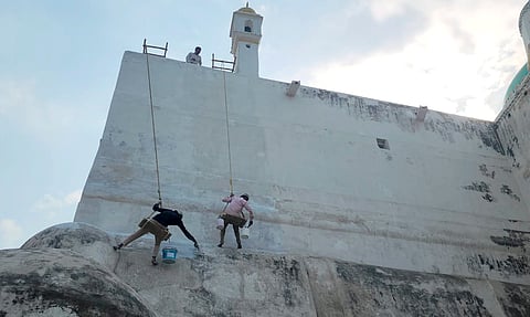 Laborers whitewash the outer wall of the Shahi Jama Masjid following an Allahabad High Court directive to the Archaeological Survey of India (ASI) to complete the task, in Sambhal, Uttar Pradesh, Sunday, March 16, 2025.