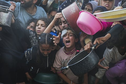 Palestinian children struggle while waiting for donated food at a distribution center in Beit Lahiya, northern Gaza Strip, Sunday, March 16, 2025.