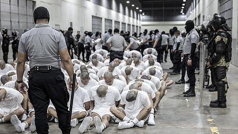 In this photo provided by El Salvador's presidential press office, a prison guard transfers deportees from the US alleged to be Venezuelan gang members, to the Terrorism Confinement Center in Tecoluca, El Salvador