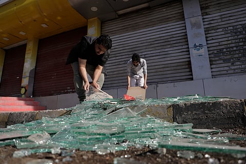 Yemenis clean debris in front of their shops after a U.S. airstrikes in Sanaa, Yemen, Sunday, March 16, 2025.