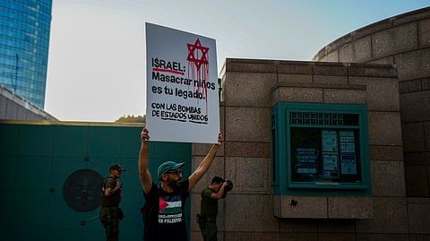 A pro-Palestinian demonstrator holds up a sign that reads in Spanish, "Israel: Massacring children is your legacy. With bombs from the United States," while protesting Israeli attacks on Gaza, in front of the U.S. embassy in Santiago, Chile, Tuesday, March 18, 2025.