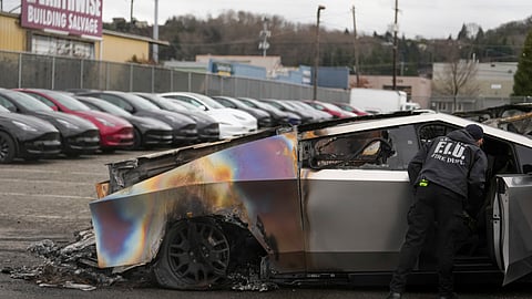 A member of the Seattle Fire Department inspects a burned Tesla Cybertruck at a Tesla lot in Seattle, Monday, March 10, 2025.