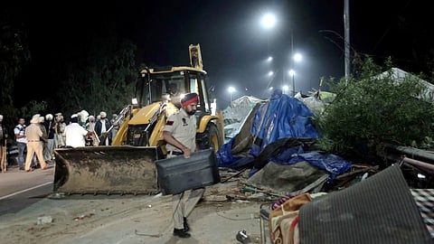 A backhoe loader being used to dismantle temporary structures set up by agitating farmers during an eviction drive by the Punjab Police to remove them from the Shambhu border, in Patiala district, Wednesday night.