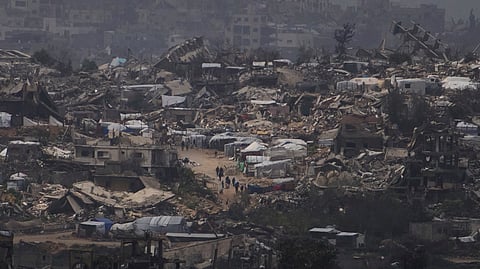 People walking surrounded by buildings destroyed during the Israeli air and ground offensive in the Gaza Strip are seen from southern Israel, Thursday, March 20, 2025.