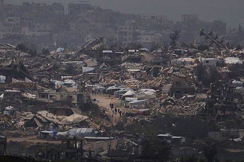 People walking surrounded by buildings destroyed during the Israeli air and ground offensive in the Gaza Strip are seen from southern Israel, Thursday, March 20, 2025.