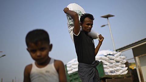 A Rohingya refugee carries a food ration sack on his back from a distribution center in Cox Bazar, Bangladesh, March 13, 2025.