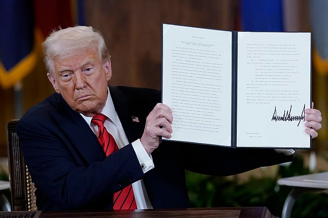 President Donald Trump holds up an executive order in the East Room of the White House in Washington, Thursday, March 20, 2025.