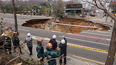 Rescue authorities inspect a sinkhole on an intersection in Seoul, South Korea, Tuesday, March 25, 2025.