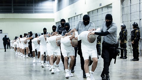 In this photo provided by El Salvador's presidential press office, prison guards transfer deportees from the US, alleged to be Venezuelan gang members, to the Terrorism Confinement Center in Tecoluca, El Salvador, Sunday, March 16, 2025.