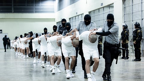 In this photo provided by El Salvador's presidential press office, prison guards transfer deportees from the U.S., alleged to be Venezuelan gang members, to the Terrorism Confinement Center in Tecoluca, El Salvador, Sunday, March 16, 2025.