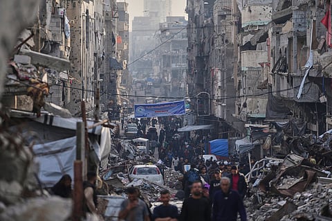 Palestinians walk amid the destruction caused by the Israeli air and ground offensive at Al-Shati camp, Gaza City, Tuesday, March 25, 2025.