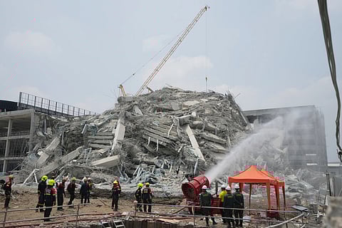 Rescuers spray water to reduce dust in Bangkok, Thailand, Saturday, March 29, 2025, while searching for victims at the site of a high-rise building under construction that collapsed after Friday's earthquake.