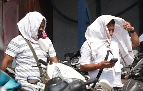 Two person covering their head with towel to protect from scorching heat in Bhubaneswar on Friday.