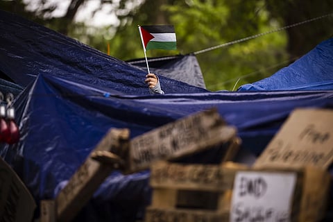 A protester waves a Palestinian flag at the University of New Mexico Palestine Solidarity encampment in Albuquerque, N.M., on May 14, 2024.