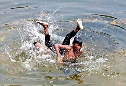 Two youths enjoying a bath in the Puri canal to beat the heat in Bhubaneswar.