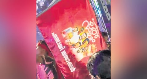 A CPM worker holding a flag featuring images of Sooraj murder convicts, during a temple festival procession