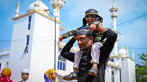 A man carry his son on shoulder as Muslims took part in namaz at Madarse Wali Masjid at Jadupur on the occasion of Eid in Bhubaneswar on Monday.