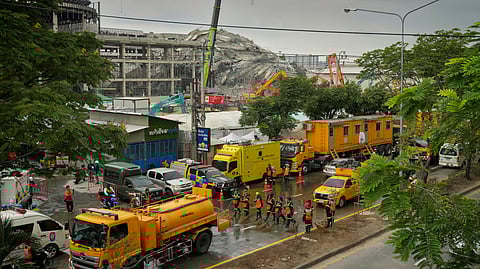 Workers clean and wash the road outside the site of an under construction high-rise building that collapsed after an earthquake in Bangkok, Thailand, Thursday, April, 3, 2025.
